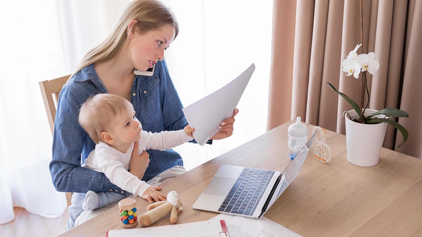 Self-care is important for this Working mom talking on the phone with child in her lap